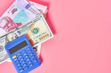 Pembe arka planda yığınla para ve hesap makinesi. Ödeme kavramı