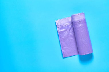 Mavi arka planda mor, tek kullanımlık plastik bir çöp torbası. Uzayı kopyala Üst görünüm
