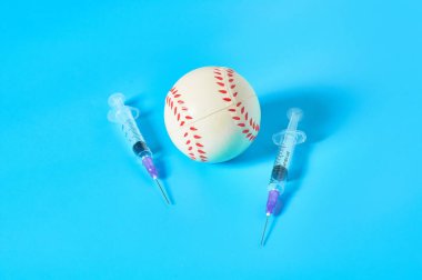Mavi arka planda şırınganın yanında beyzbol topu var. Profesyonel sporda doping kavramı. Rehabilitasyon, yarışmadan sonra tedavi. Turnuvada kullanılan yasadışı ilaçlar