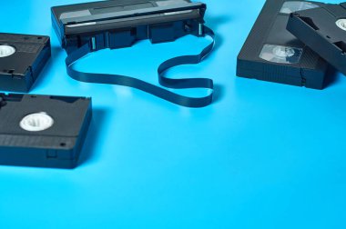 Bir sürü eski siyah plastik video kasetler mavi masanın üzerinde duruyor. 90 'ların konsepti. Boşluğu kopyala