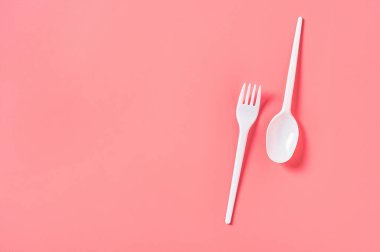Pembe arka planda tek kullanımlık beyaz kaşık ve çatal. Çevreyi, ekolojiyi, piknik, parti ve diğer etkinlikleri kurtarma kavramı. Üst Manzara. Boşluğu kopyala