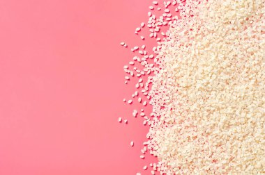Pembe arka planda dağınık beyaz pirinç taneleri. Uzayı kopyala Üst görünüm