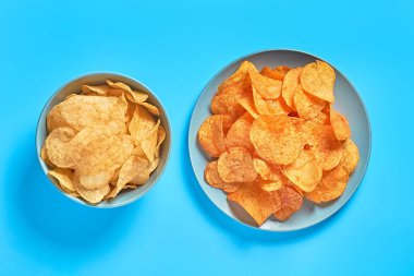 Gri seramik tabak ve mavi arka planda patates cipsi dolu bir kase. Üst Manzara. Yakın plan.