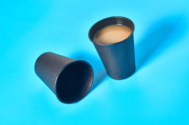 Mavi arka planda sıcak içecekler için dolu ve boş bir karton bardak. Çevre koruma kavramı, kahve molası, ekoloji, çöp geri dönüşümü