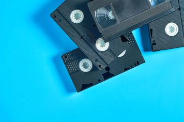 Eski siyah plastik kaset yığını mavi masanın üzerinde duruyor. 90 'ların konsepti. Uzayı kopyala Üst görünüm