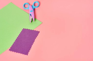 Dekoratif kıvrımlı kağıt kesme makası ve pembe zemin üzerinde dalga sınırı olan el işi için boş kağıtlar. El yapımı, boş zaman ve anaokulu eğitimi kavramı