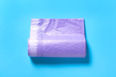 Mavi arka planda mor, tek kullanımlık plastik bir çöp torbası. Üst Manzara. Yakın plan.