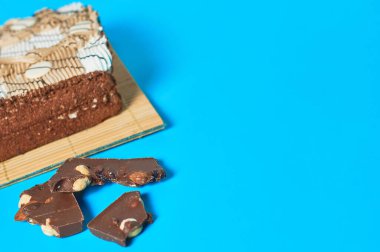 Bambu hasırının üzerinde damalı dikdörtgen şeklinde bir pasta var. Parti masasında fındıklı çikolata var. Kutlama konsepti. Metin için boşluk