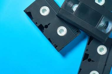 Bir sürü eski siyah plastik video kasetler mavi masanın üzerinde duruyor. 90 'ların konsepti. Uzayı kopyala Düz yatıyordu
