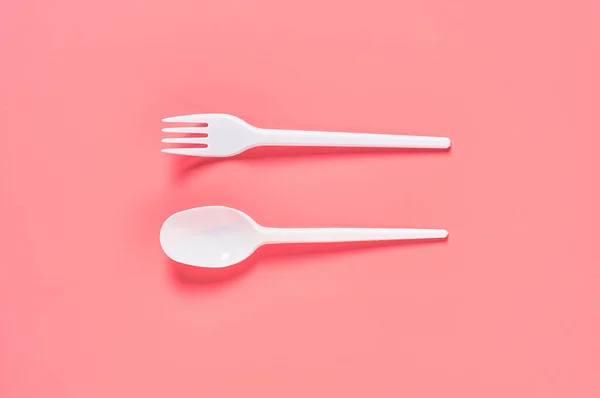 粉红背景上的白色即弃勺子和叉子 拯救环境 野餐娱乐 派对和其他活动的概念 顶部视图 — 图库照片