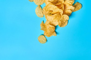 Mavi arka planda bir sürü kızarmış patates cipsi. Mesaj için yer var. Üst görünüm