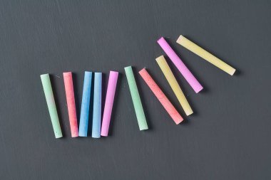 Siyah karatahtaya bir sürü renkli tebeşir parçaları serpiştirdim. Üst Manzara. Yakın plan.