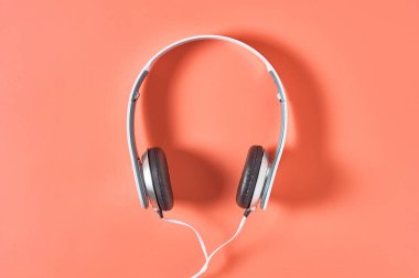Kablolu ve turuncu arka planlı modern beyaz kulaklıklar. Müzik konsepti. Üst görünüm