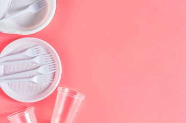 Pembe arka planda tek kullanımlık plastik aletler. Çevreyi, ekolojiyi, piknik, parti ve diğer etkinlikleri kurtarma kavramı. Uzayı kopyala Üst görünüm