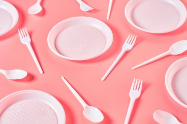 Pembe arka plana saçılmış tek kullanımlık plastik kaplar. Piknik, parti ve diğer etkinliklerde tasarruf ortamı, ekoloji, eğlence kavramı