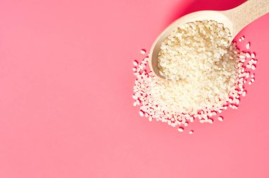Pembe arka planda beyaz pirinç tanecikli tahta kaşık. Uzayı kopyala Üst görünüm