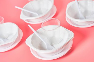 Pembe arka planda tek kullanımlık plastik aletler. Piknik, parti ve diğer etkinliklerde tasarruf ortamı, ekoloji, eğlence kavramı