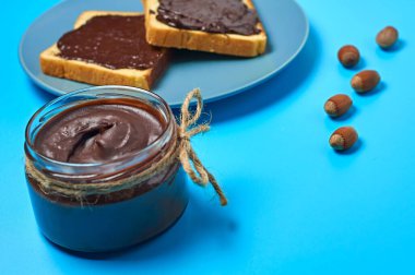 Mutfaktaki mavi masada duran vanilyalı ekmek ve fındıklı tabağın yanında erimiş çikolata ya da krema dolu cam kavanoz. Besleyici kahvaltı ya da öğle yemeği kavramı