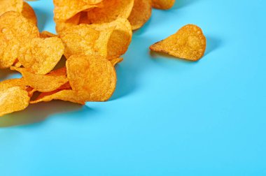 Baharatlı patates cipsi, mavi arka planda. Metin için boşluk