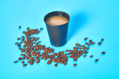 Mavi arka planda dağınık fasulyelerin yanında tam siyah karton kahve bardağı. Çevre koruma kavramı, kırılma, ekoloji