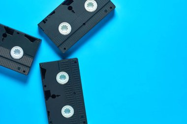 Dağıtılmış eski siyah plastik video kasetler mavi masanın üzerinde duruyor. 90 'ların konsepti. Uzayı kopyala Üst görünüm