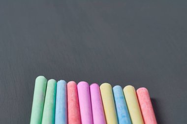 Siyah karatahtanın üzerinde renkli tebeşir parçaları var. Boşluğu kopyala