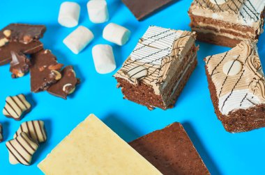 Çeşitli tatlılar, şekerler, şekerlemeler, çikolatalar partide mavi masanın üzerinde. Kutlama konsepti. Yakın plan.