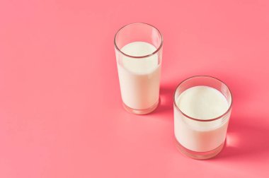 İki bardak taze süt, yoğurt ya da pembe arka planda kefir. Metin için boşluk