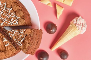 Farklı tatlıların yanında çikolatalı pasta pembe masanın üzerinde yatıyor. Üst Manzara. Yakın plan.