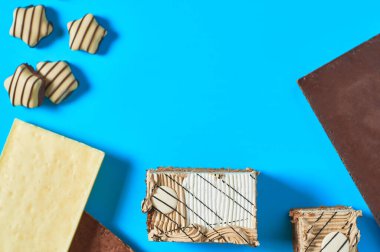 Farklı çikolata ve şekerlemelerin yanında üç dikdörtgen pasta partideki mavi masada duruyor. Kutlama konsepti. Mesaj için yer var. Üst görünüm