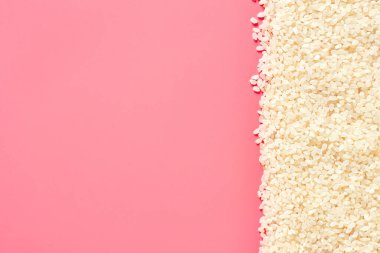 Pembe arka planda dağınık beyaz pirinç taneleri. Uzayı kopyala Üst görünüm