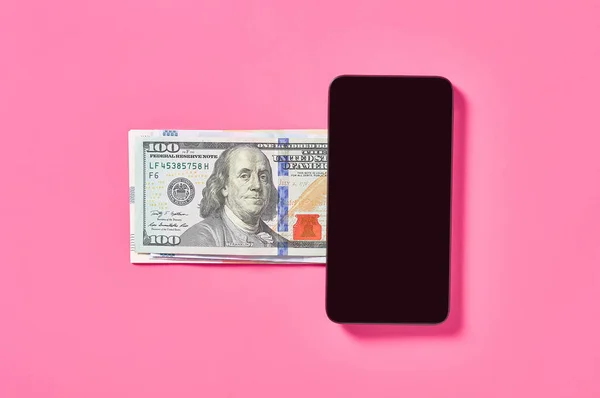 Smartphone and banknote of dollars on pink background. Concept of mobile banking. Online shopping from home. Distancing control financial balance