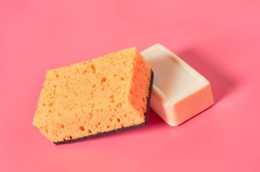 Pembe arka planda süngerin yanında bir kalıp sabun. Hijyen ve temizlik kavramı