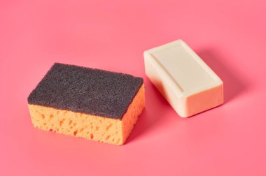 Pembe arka planda süngerin yanında bir kalıp sabun. Hijyen ve temizlik kavramı