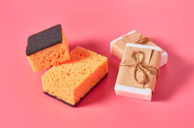 Pembe arka planda süngerlerin yanına dizilmiş sabun kalıpları. Hijyen ve temizlik kavramı