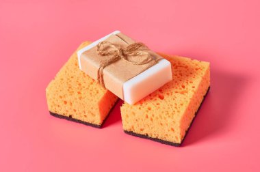 Pembe arka planda süngerlerin yanına dizilmiş sabun kalıpları. Hijyen ve temizlik kavramı