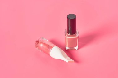 Pembe arka planda iki şişe lüks tırnak cilası. Güzellik ve moda konsepti