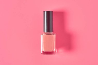 Pembe arka planda bir şişe lüks tırnak cilası. Güzellik ve moda konsepti