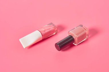 Pembe arka planda iki şişe lüks tırnak cilası. Güzellik ve moda konsepti