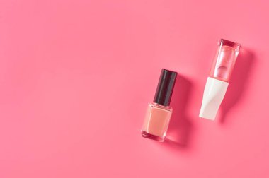 Pembe arka planda iki şişe lüks tırnak cilası. Güzellik ve moda konsepti