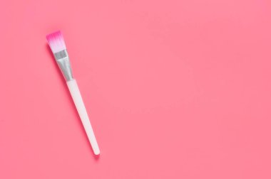 Pembe arka planda bir kozmetik fırça. Güzellik ve cilt bakımı