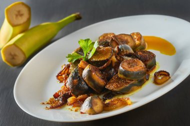 Beton masadaki restoranda soğanlı ve körili kızarmış muz servis ettim.