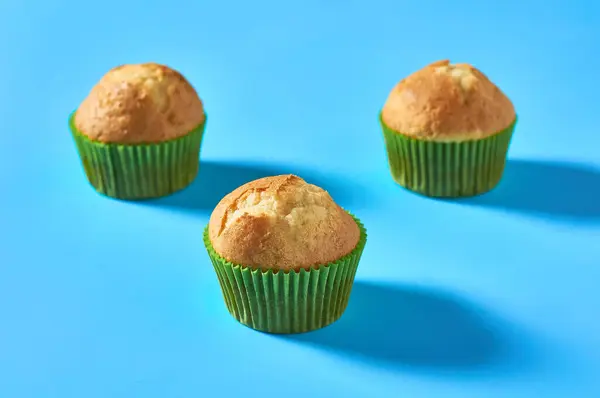 Tři Nadýchané Muffiny Zelené Papírové Formě Modrém Pozadí — Stock fotografie