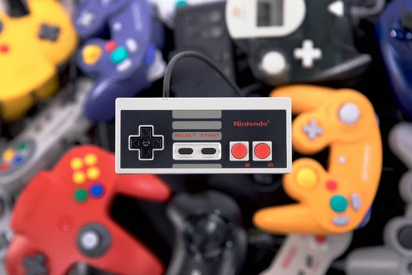 Un controlador NES de Nintendo flotando sobre una pila de video retro Ga — Foto de Stock