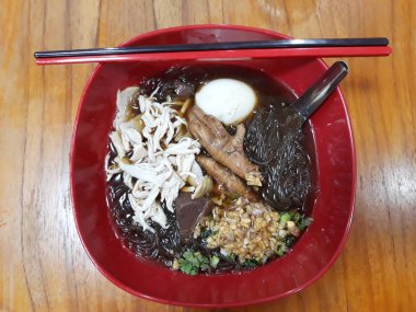 Cam kırmızı bir kase tavuk, derin kızarmış sarımsak ve bazı sebze dilimlenmiş kahverengi çorba tavuk ayağı, bir haşlanmış yumurta şehriye. Yemek çubukları ve bir kaşık ile kahverengi masaya yerleştirerek bir kase