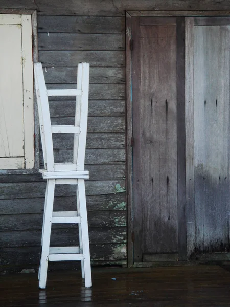 two white stool chairs in front of the brown wooden wall and door