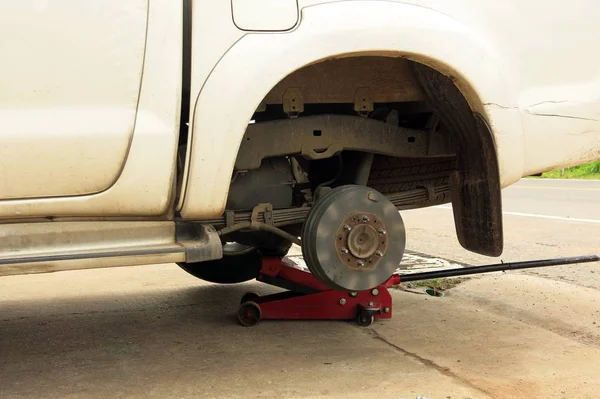 beyaz bir kirli araba lastik olmadan. Bu işlem tamirinde. Tamirci çıkar lastik tamir için.