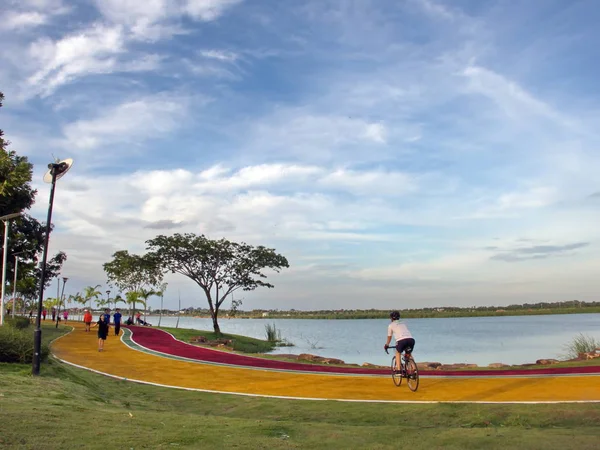 Khon Kaen, Thailand-Ağustos 2018: güzel parlak mavi gökyüzü, taze bir atmosfer ve iyi çevre ile gölün yanındaki parkta bisiklet şeritli üzerinde bisiklete binmek bir adam