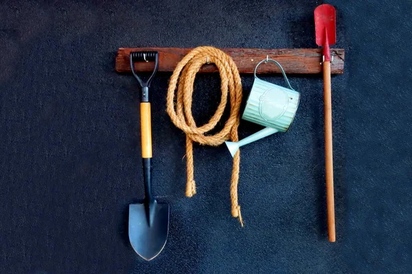 Bahçe aletleri siyah duvarda asılı