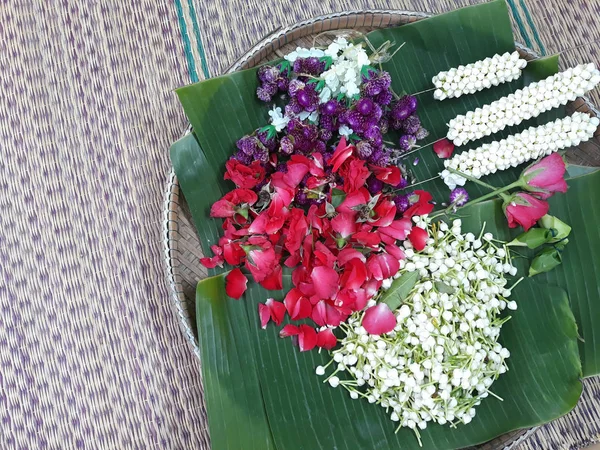 pek çok çiçek ve yaprakları üzerinde muz yaprakları bir adet harman sepete çiçek çelenk yapmak için hazırlanıyor